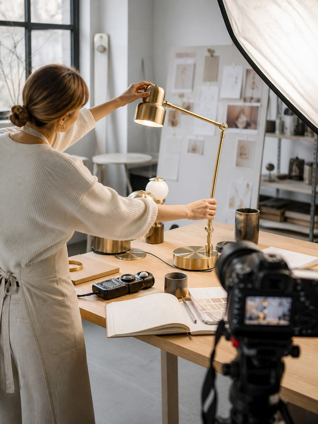 Syra adjusting a lamp in a light-filled studio